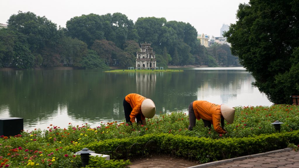 Arbeiterinnen mit typischem Reishut in Hanoi vor dem Turtle Tower